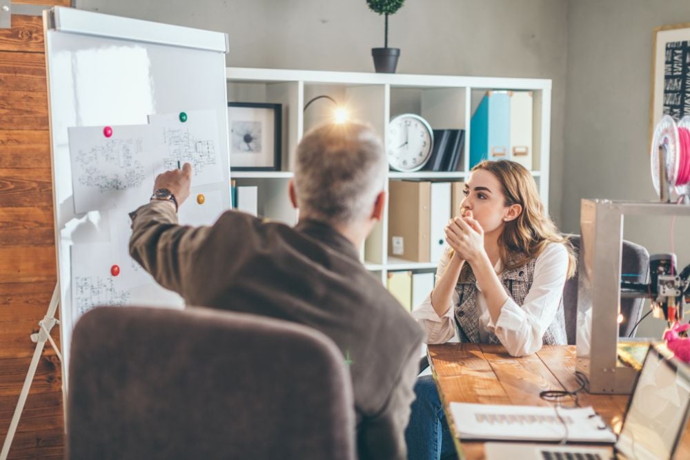 Man mentoring woman in office